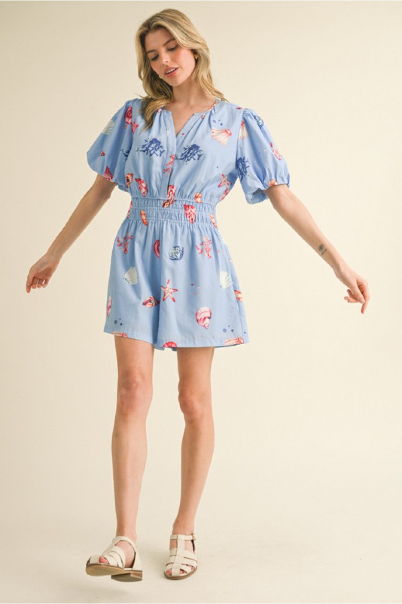 Chic blue shell print romper from a coastal boutique, featuring puff sleeves, slit neck, and side pockets for summer vibes.