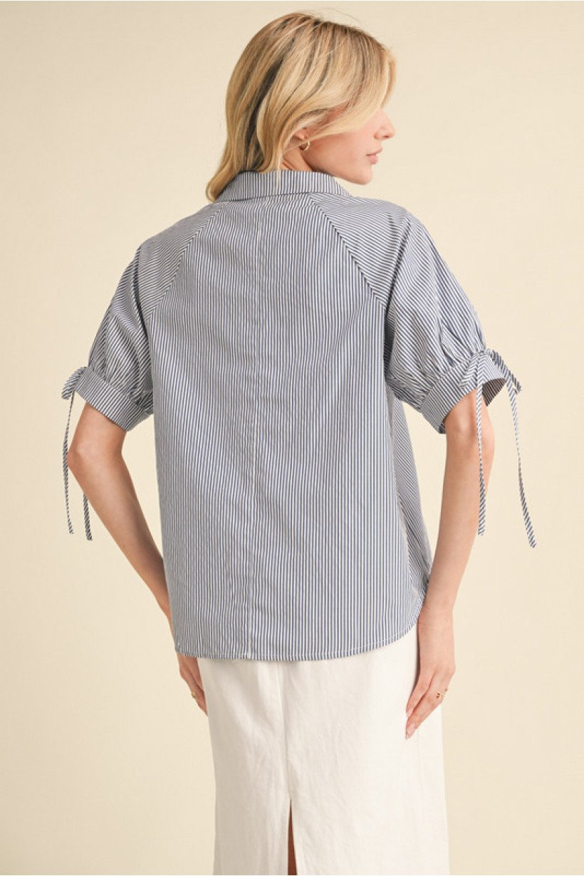 Navy striped top with bow tie cuffs, perfect for coastal boutique clothing and stylish tops for women. Ideal for casual outings.