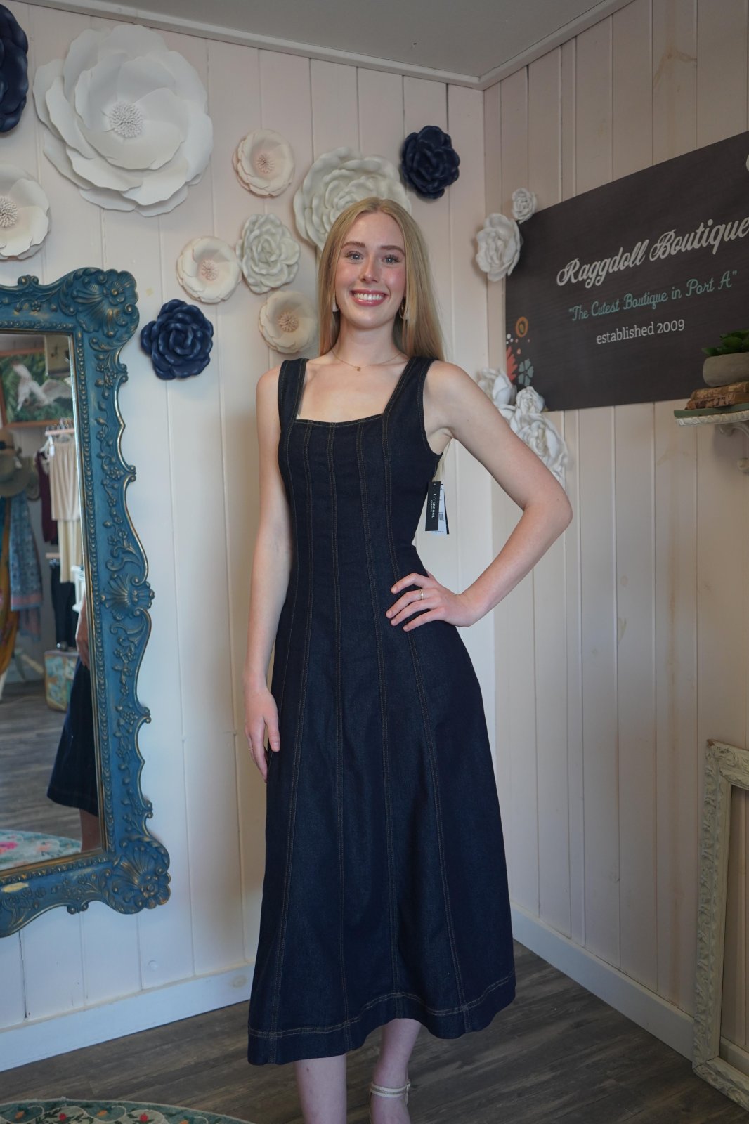 Stylish sleeveless smocked-back midi dress in indigo at a coastal boutique. Perfect for beach days and tropical vacations.