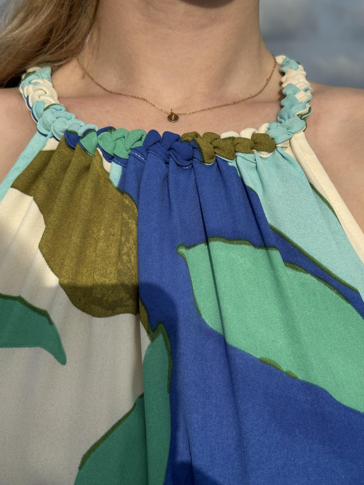 Close-up of Marisol Dress featuring tropical leaves print and unique knot-detailed neckline, perfect for summer beach parties.