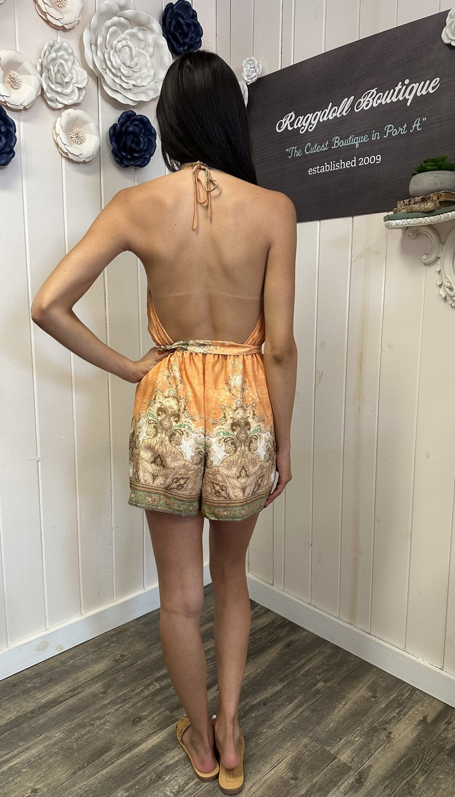 Back view of a light apricot halter romper, ideal for coastal boutique clothing and beach dresses, styled for summer vibes.