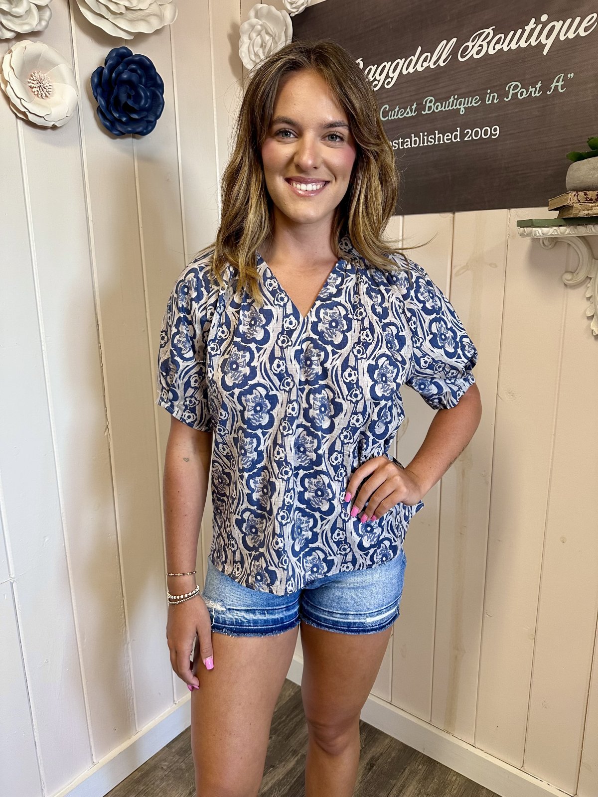 Model wearing Amaya Top from a coastal boutique, featuring a floral print and V-neck style, perfect for beach outfits.