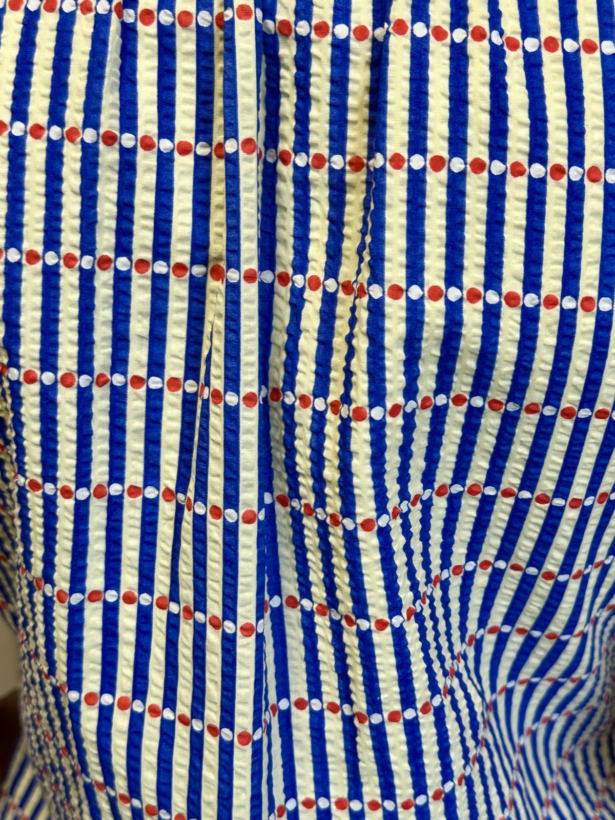 Close-up of fabric with bold blue and cream stripes, perfect for coastal boutique clothing and tropical vacation dresses.