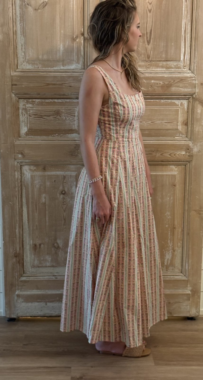 Light coral floral fit and flare midi dress showcased in a coastal boutique; perfect for summer styling and tropical vacations.