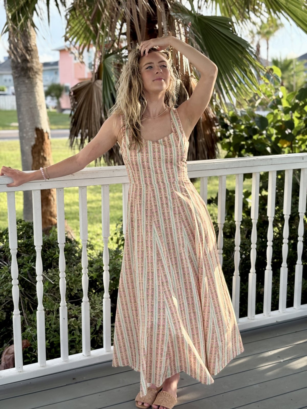 Model in light coral floral fit and flare midi dress, perfect for coastal boutique clothing and summer beach outfits.