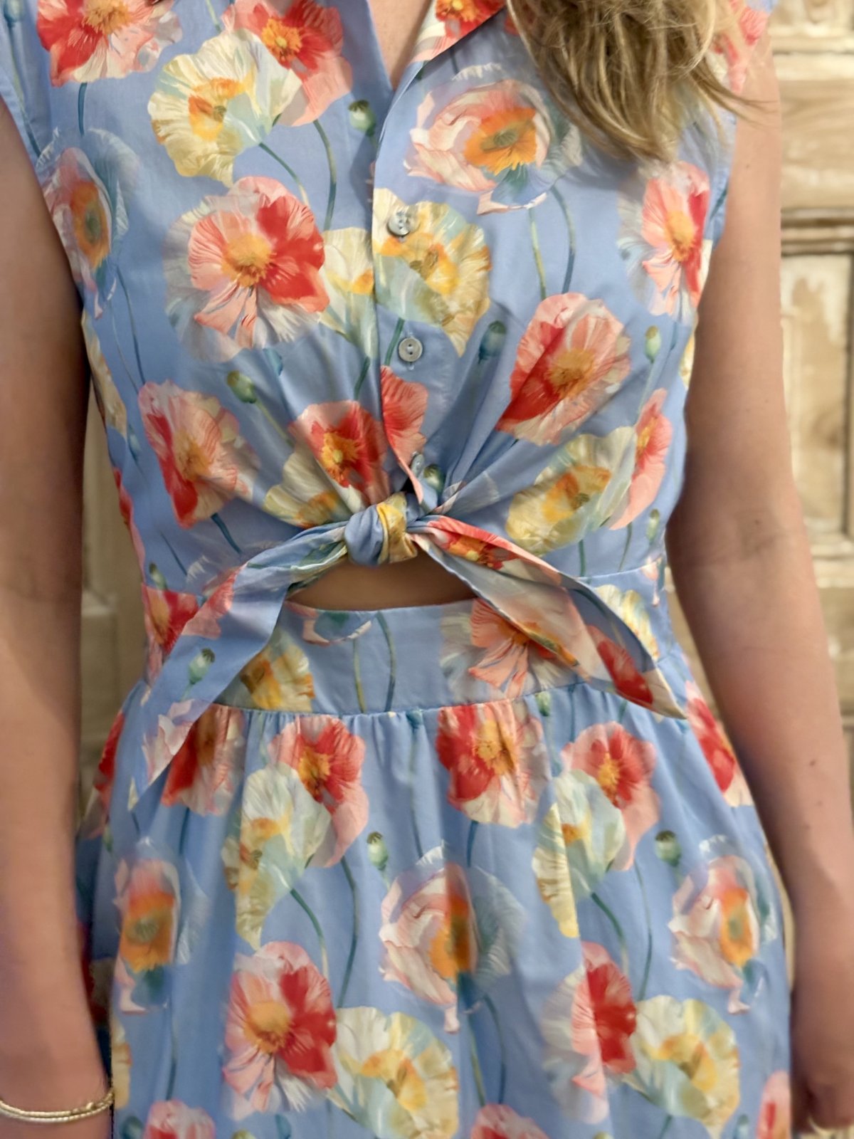 Light blue floral print sleeveless midi dress with knot tie waist, perfect for coastal boutique clothing and tropical vacations.