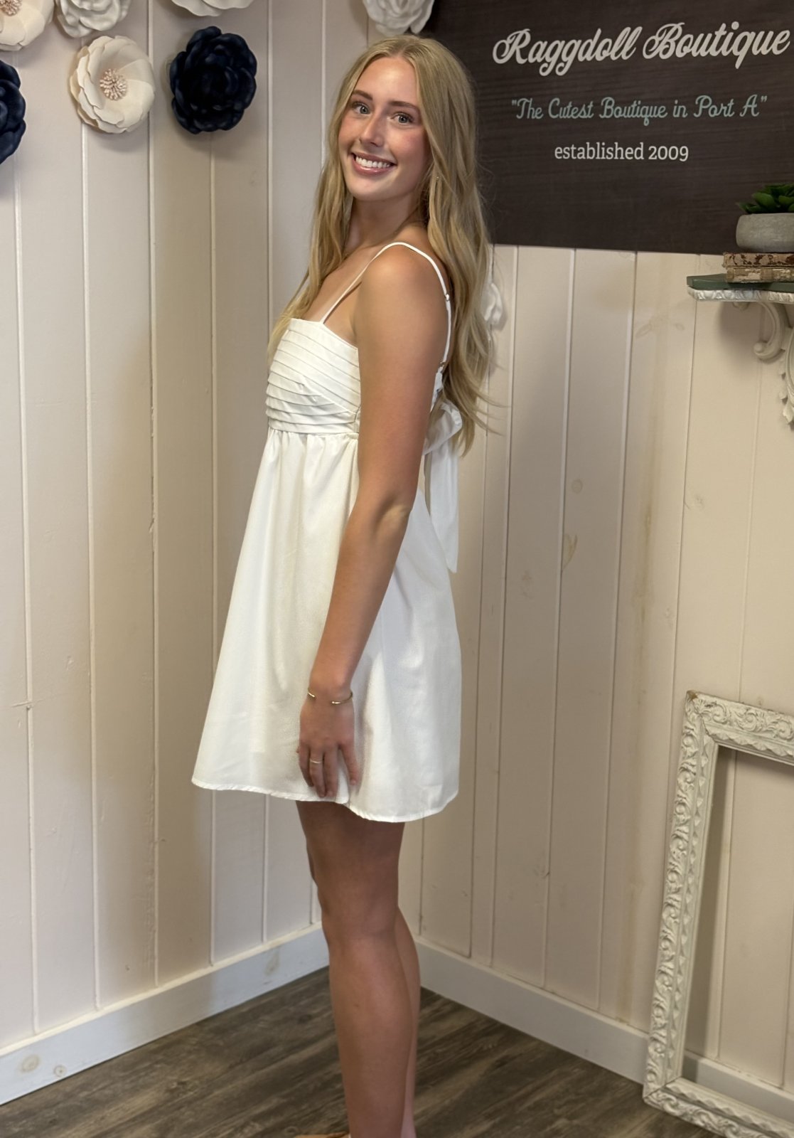 Off-white pleated dress with chic cut-out back, perfect for beach outings. Available at Raggdoll Boutique in Port Aransas.