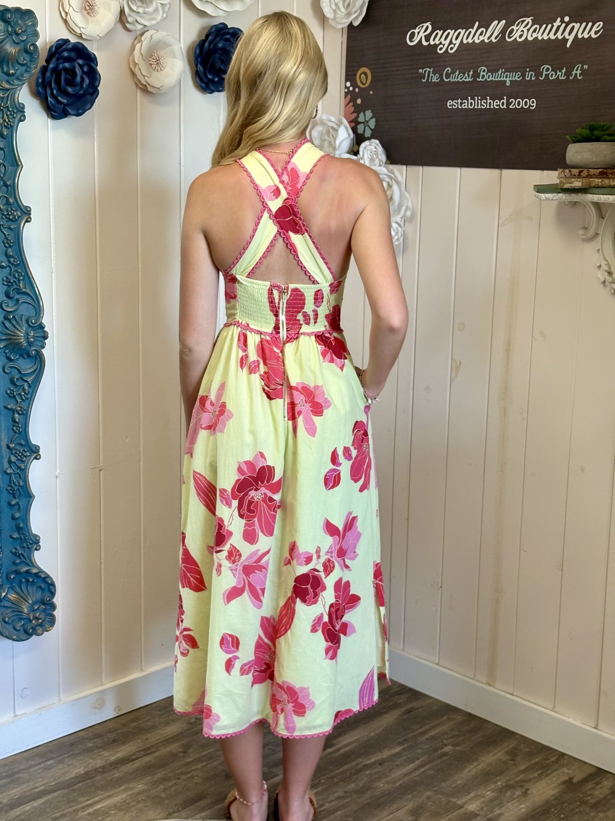 Back view of a woman in a floral midi dress from Raggdoll Boutique, ideal for coastal boutique clothing and tropical vacations.