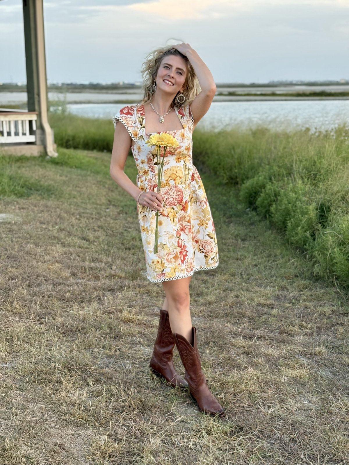 Woman wearing a floral Palmer Dress from a coastal boutique, ideal for beach outings and autumn fashion.