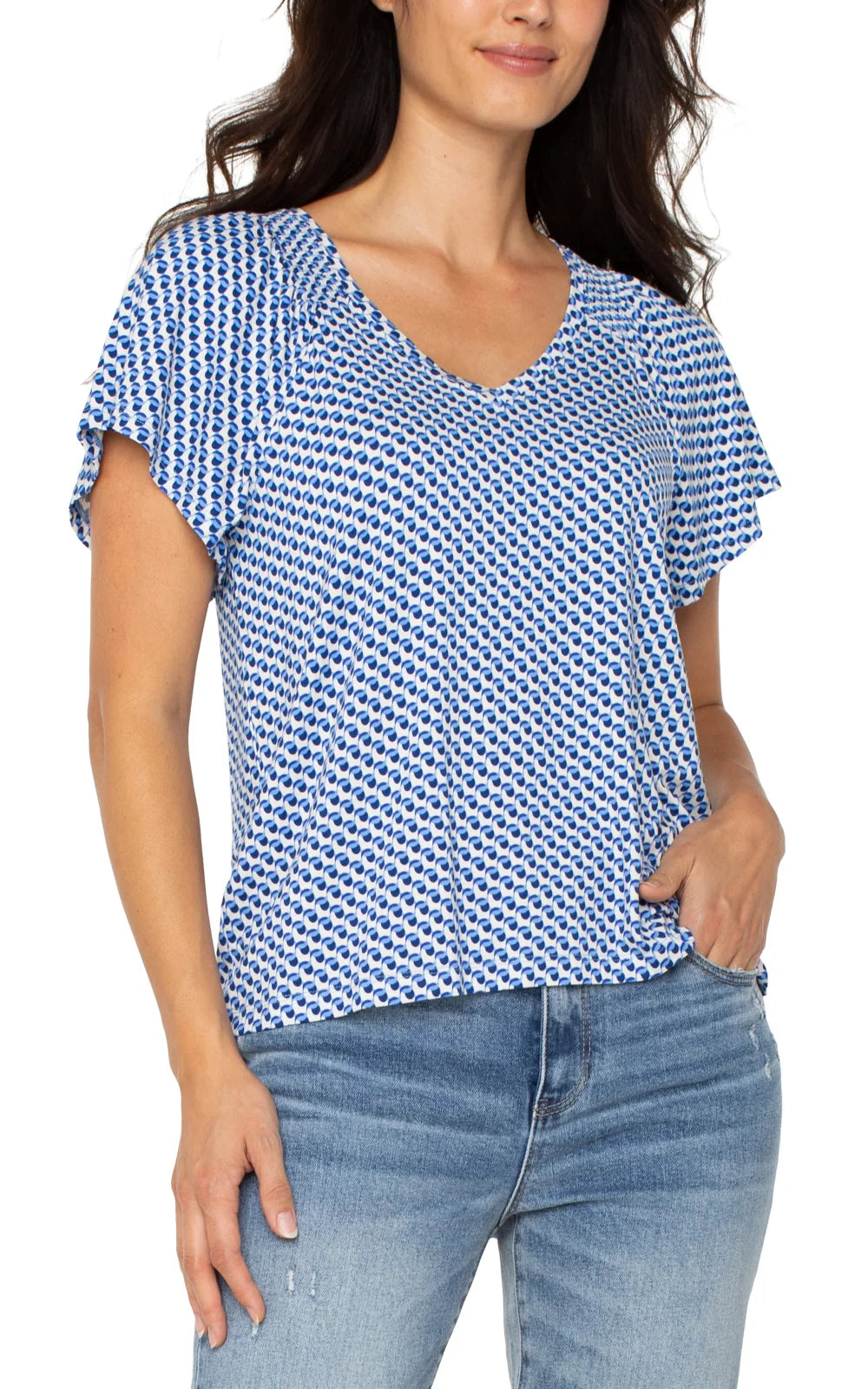 Woman wearing a blue geo flutter sleeve top, ideal for coastal boutique clothing or tropical vacation dresses.