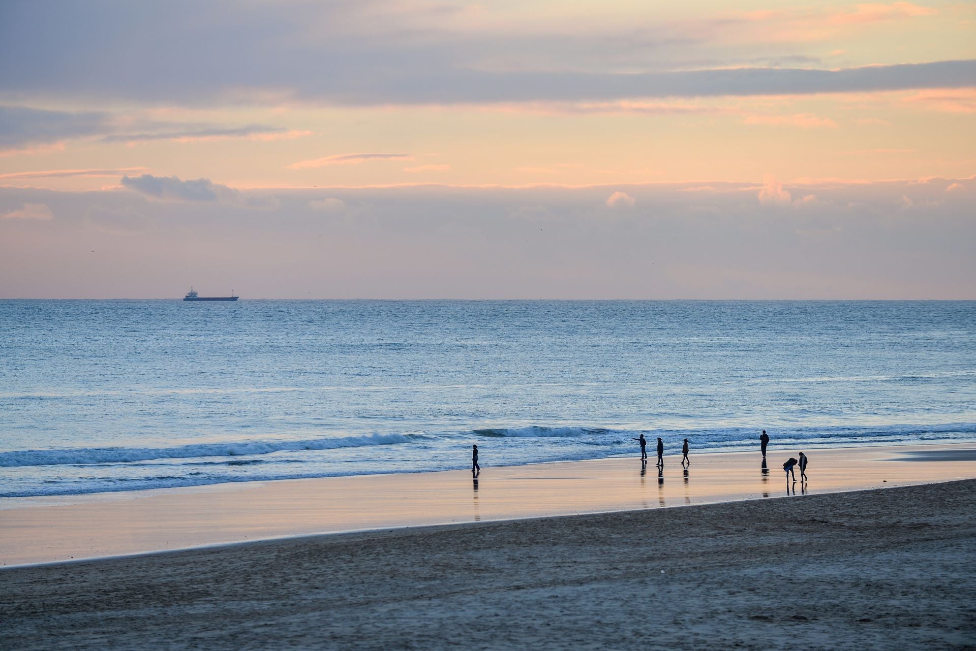 People enjoying a sunset at the beach, ideal for showcasing coastal boutique clothing and tropical vacation dresses.