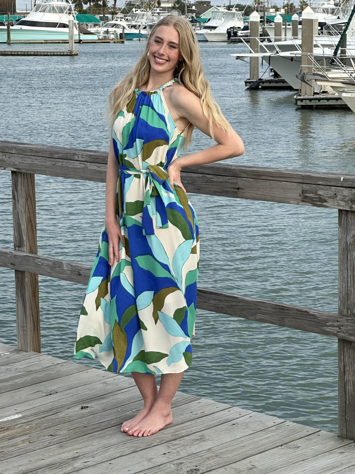 Model showcasing the vibrant Marisol Dress with tropical leaves design, perfect for beach outings from a coastal boutique.
