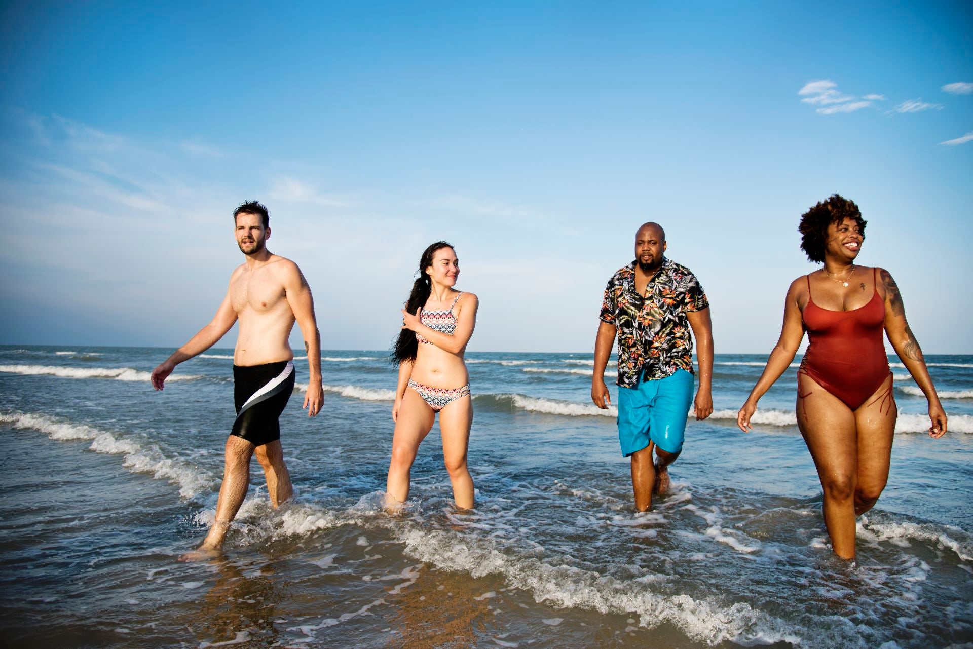 Group of friends enjoying a beach day in stylish swimsuits, perfect for summer outfits at Raggdoll Boutique.