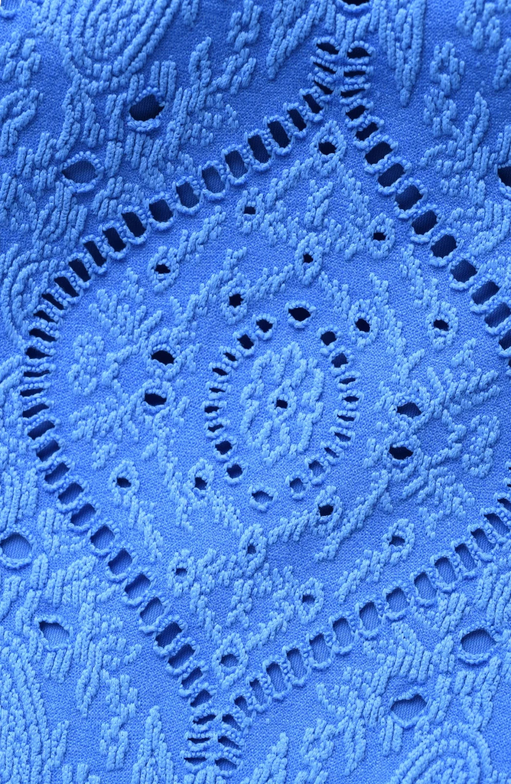 Close-up of blue jacquard fabric featuring lace-inspired patterns, ideal for coastal boutique clothing and tropical vacation dresses.