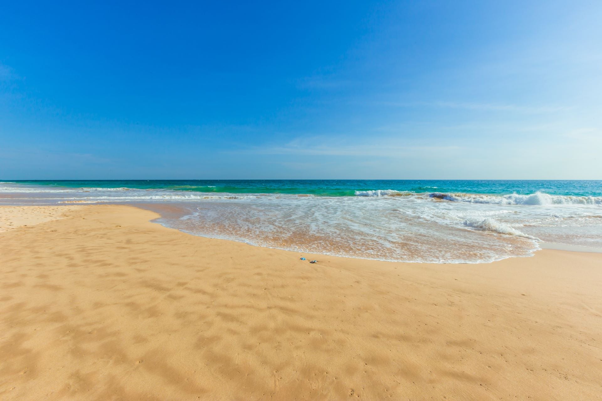 Scenic beach view with clear blue waters and golden sand, ideal for showcasing coastal boutique clothing and beach dresses.