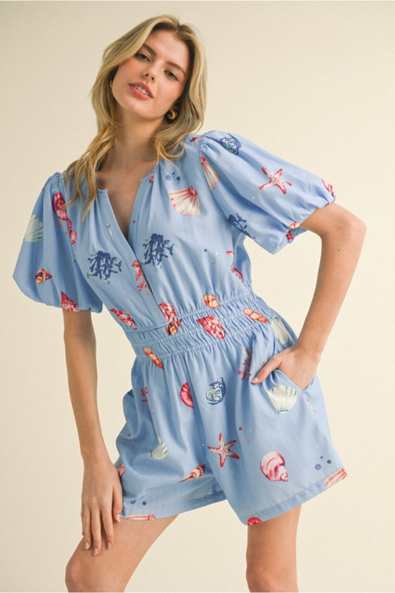 Light blue denim romper featuring button details, perfect for coastal boutique clothing and tropical vacation dresses.