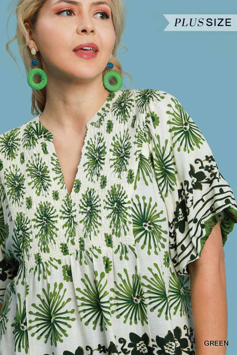 Model in a plus size floral top featuring green patterns, showcasing coastal boutique clothing for curvy women.