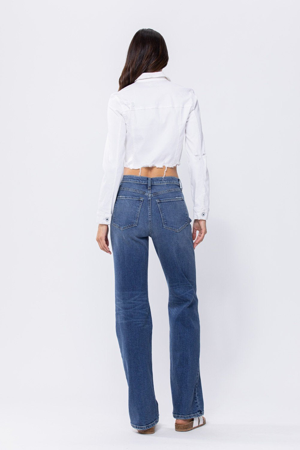Model wearing WHITE CROP SLIGHT DISTRESS JACKET with high-waisted jeans, showcasing trendy coastal style from Raggdoll Boutique.