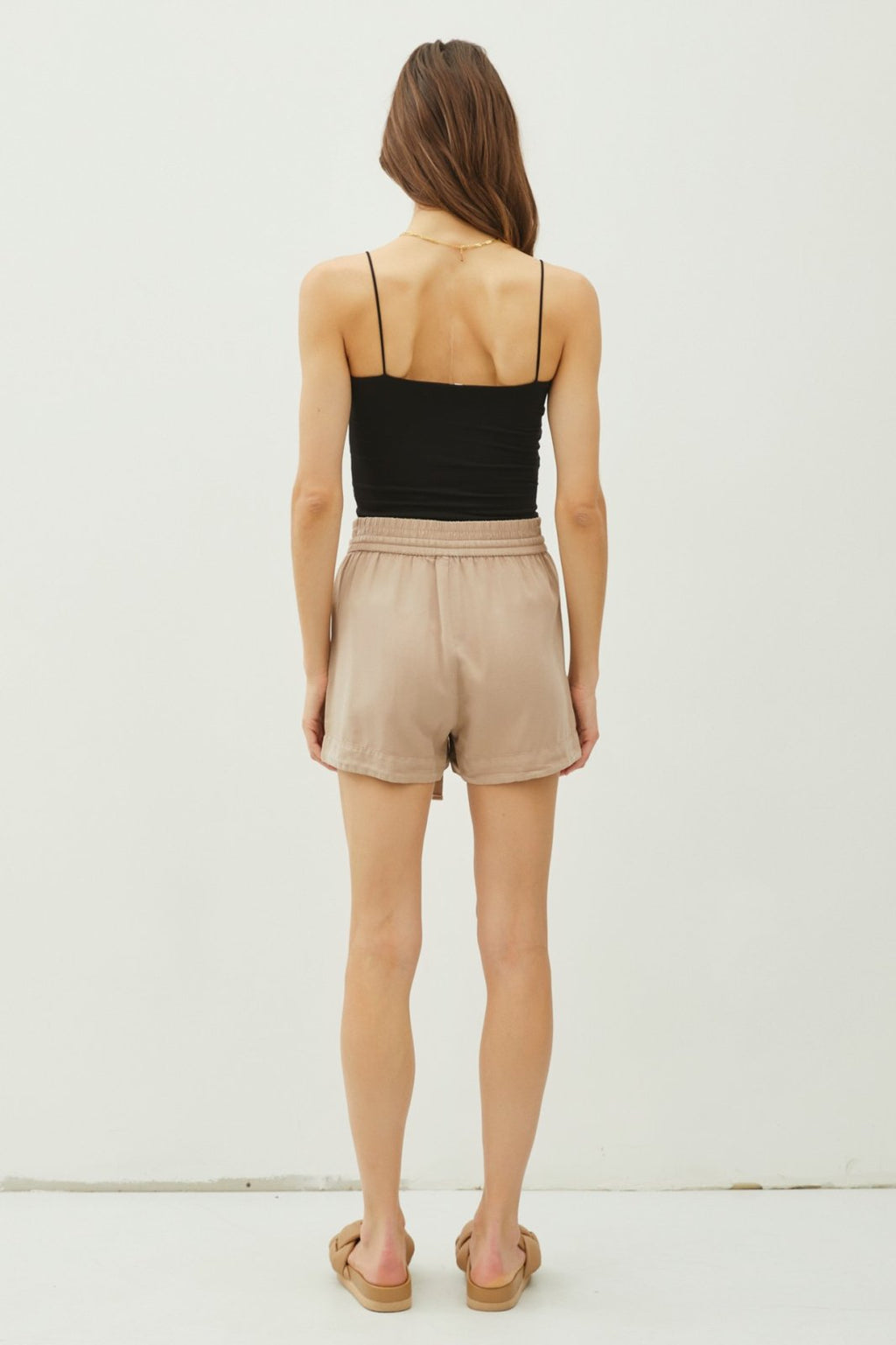 TENCEL SHORTS WITH DRAWSTRING- SAND worn with a black top, showcasing trendy coastal style from Raggdoll Boutique.