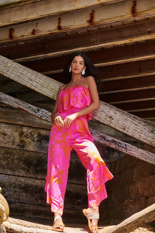 Model wearing FUN FLORAL STRAPLESS JUMPSUIT from Raggdoll Boutique in a coastal setting, showcasing trendy summer outfits.