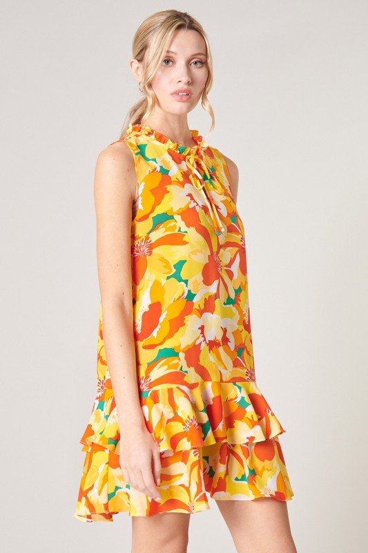 Model wearing a vibrant floral dress from Raggdoll Boutique, showcasing trendy coastal style for summer outfits Texas, IN THE TROPICS.
