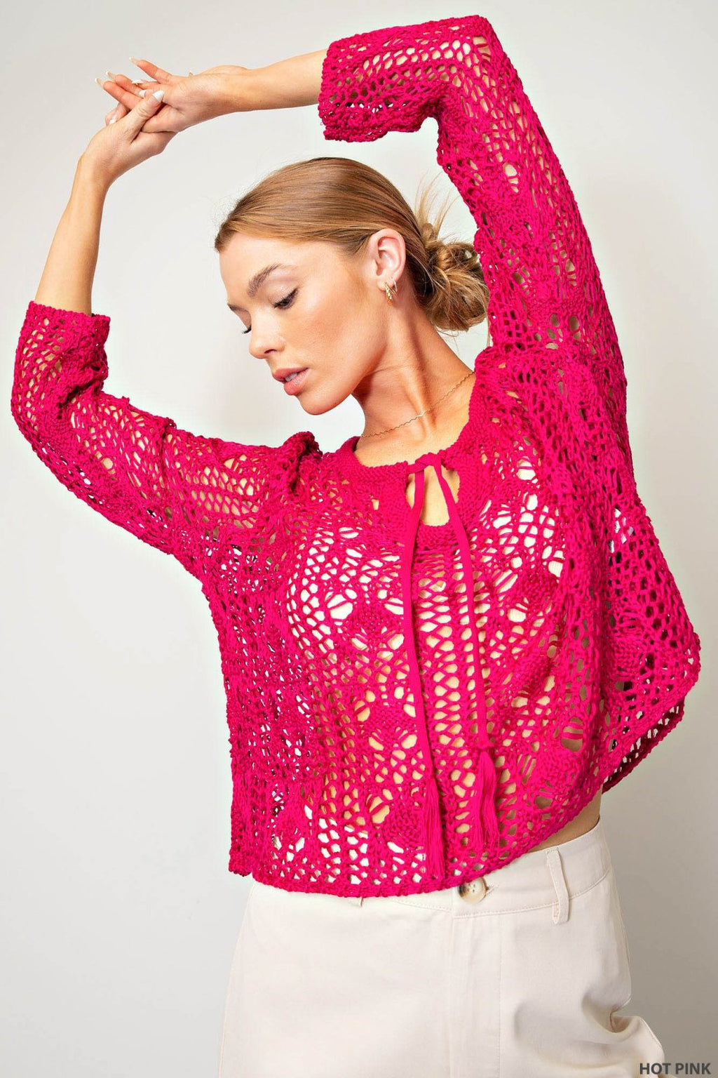 Stylish hot pink crocheted boho sweater at a coastal boutique, perfect for tropical vacation outfits and curvy plus size fashion.
