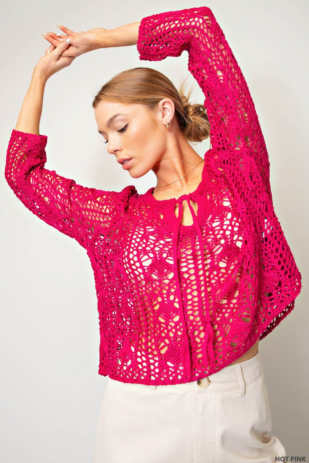 Stylish hot pink crocheted boho sweater at a coastal boutique, perfect for tropical vacation outfits and curvy plus size fashion.