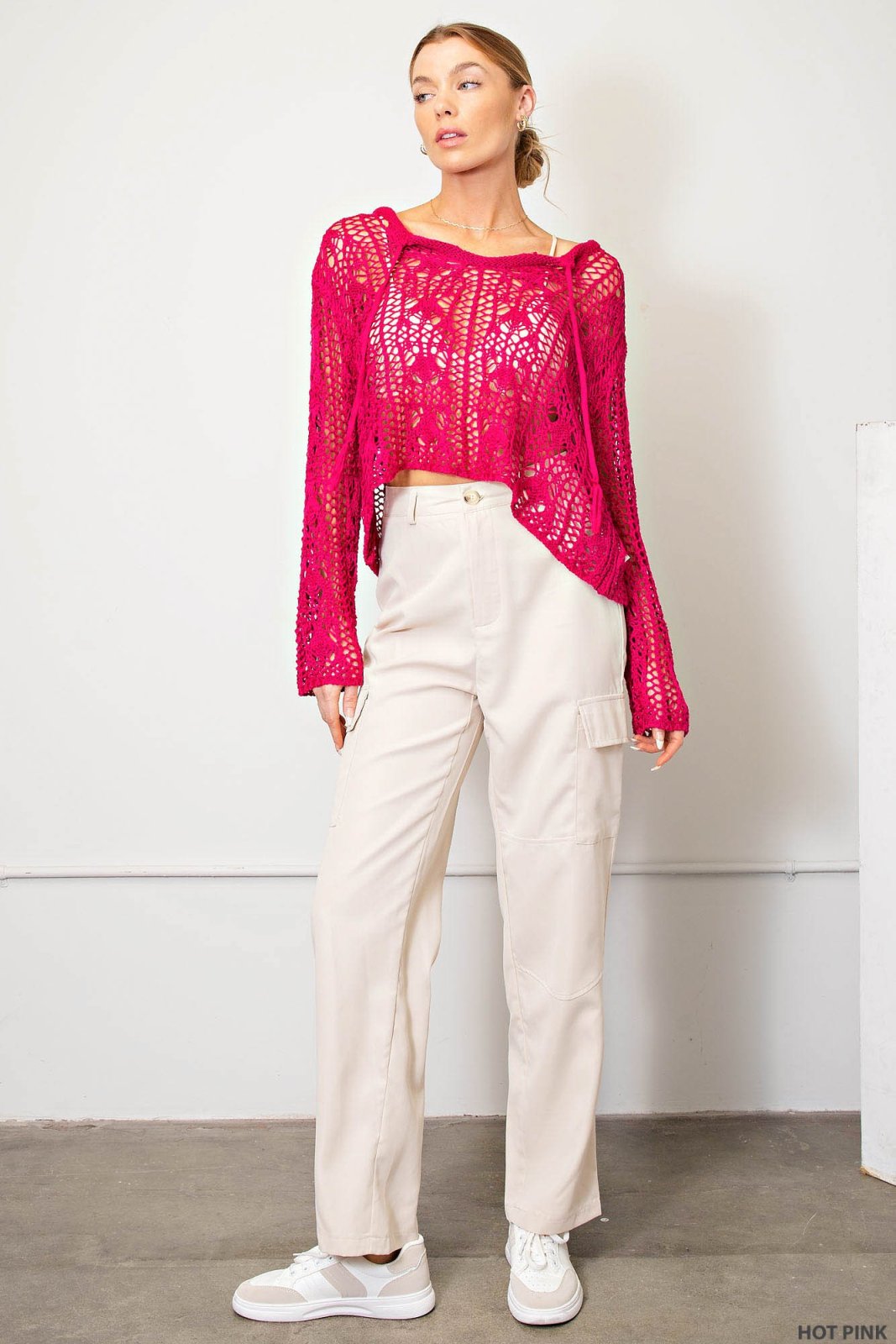 Stylish hot pink crocheted boho sweater paired with casual cream pants, perfect for coastal boutique clothing and tropical vacations.