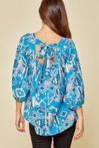 TEAL MULTI TOP WITH BACK BOW from Raggdoll Boutique features a stylish tie back and vibrant tie-dye pattern.