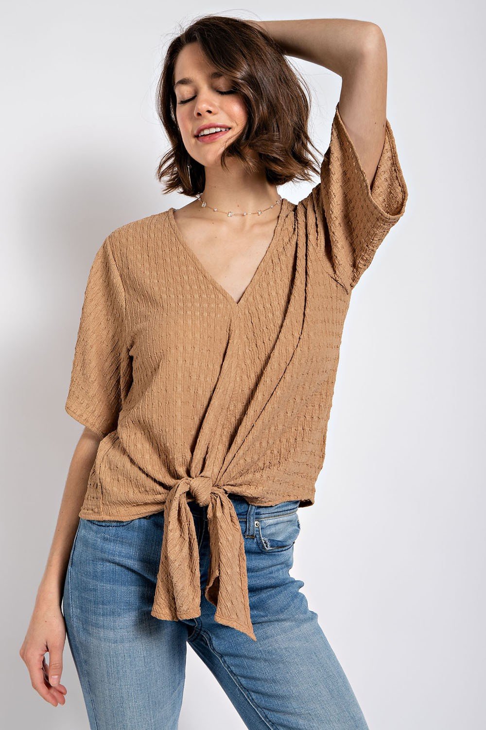 Stylish latte textured tie-front top perfect for coastal boutique clothing, paired with jeans for a chic look.