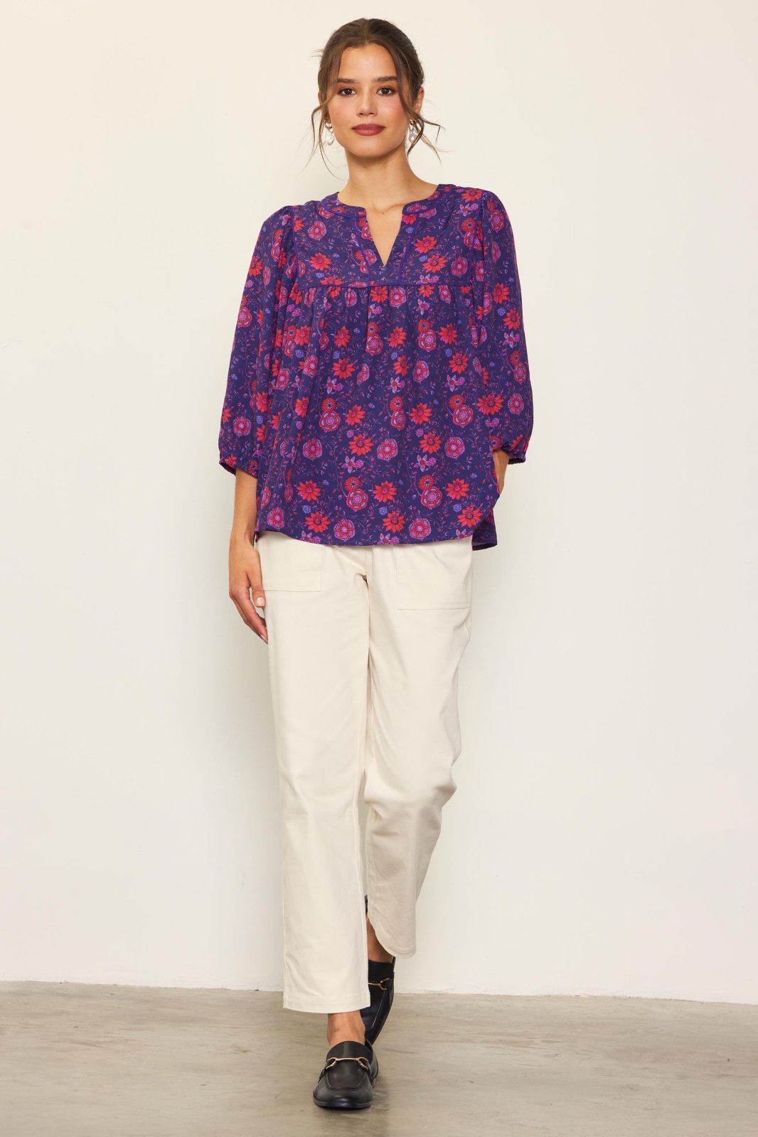 Stylish woman in a GRAPE-RED PRINTED BLOUSE paired with white pants, showcasing trendy coastal style from Raggdoll Boutique.
