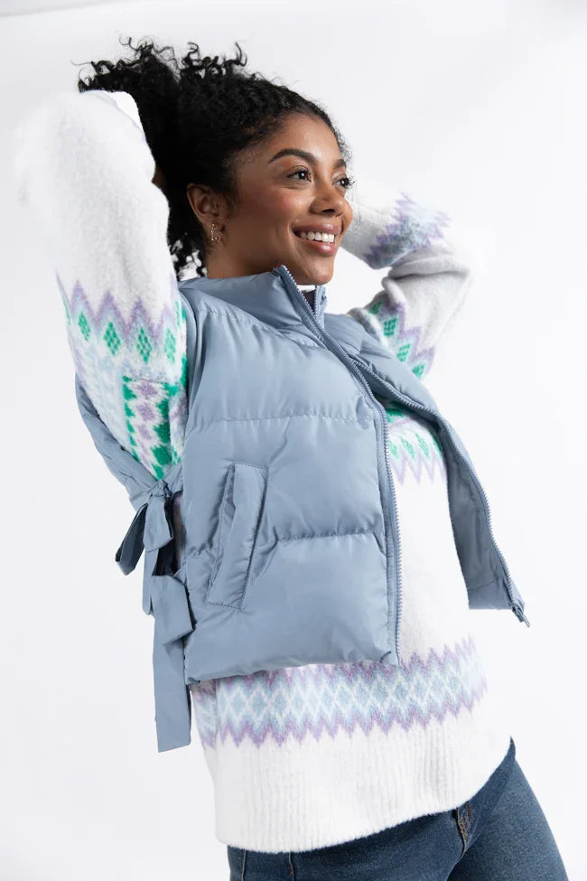 Model wearing a powder blue vest with side bows, styled with a cozy sweater, perfect for coastal boutique clothing looks.