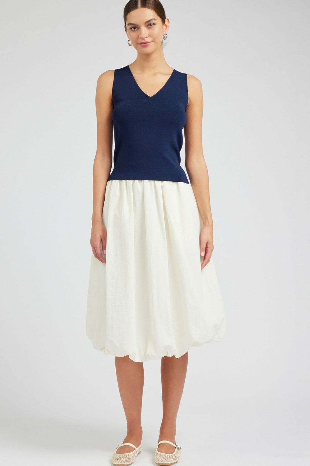 Navy V-Neck Sleeveless Sweater styled with a white skirt, perfect for coastal boutique clothing and curated women's fashion.
