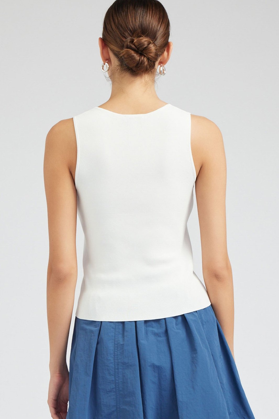 Back view of a white sleeveless V-neck sweater ideal for coastal boutique clothing and stylish tops for women.
