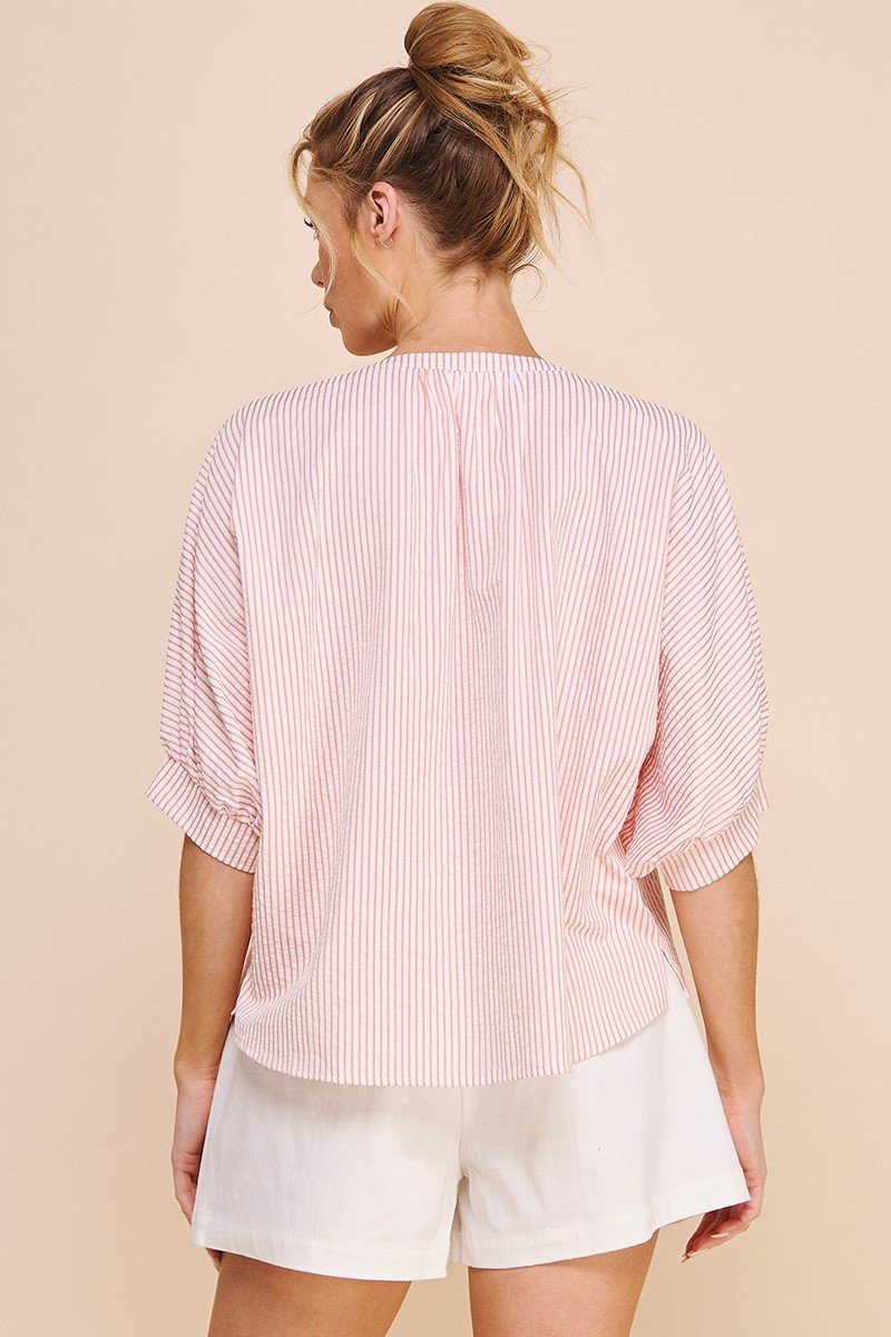 PINK PINSTRIPE TOP displayed on a model wearing shorts, showcasing trendy coastal style from Raggdoll Boutique.