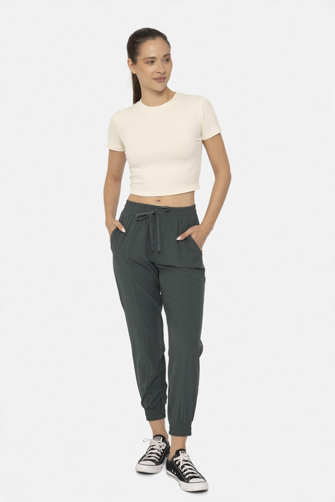 Woman in jungle green cuffed joggers and white crop top, showcasing coastal boutique clothing for stylish beach outfits.