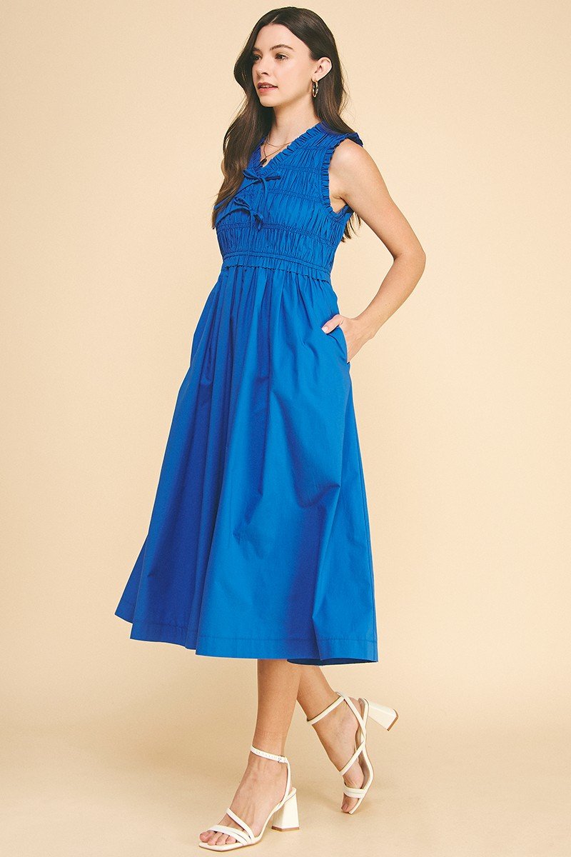 Summer blue midi dress with smocking detail, perfect for coastal boutique clothing and tropical vacations. Elegant V-neckline.