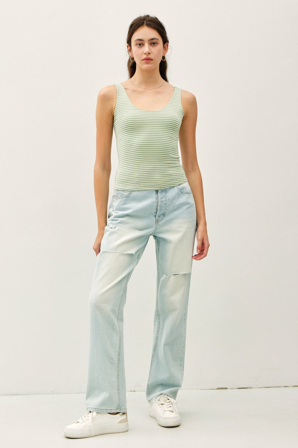 Stylish pistachio stripe tank top paired with light blue jeans, perfect for summer layering from a coastal boutique.