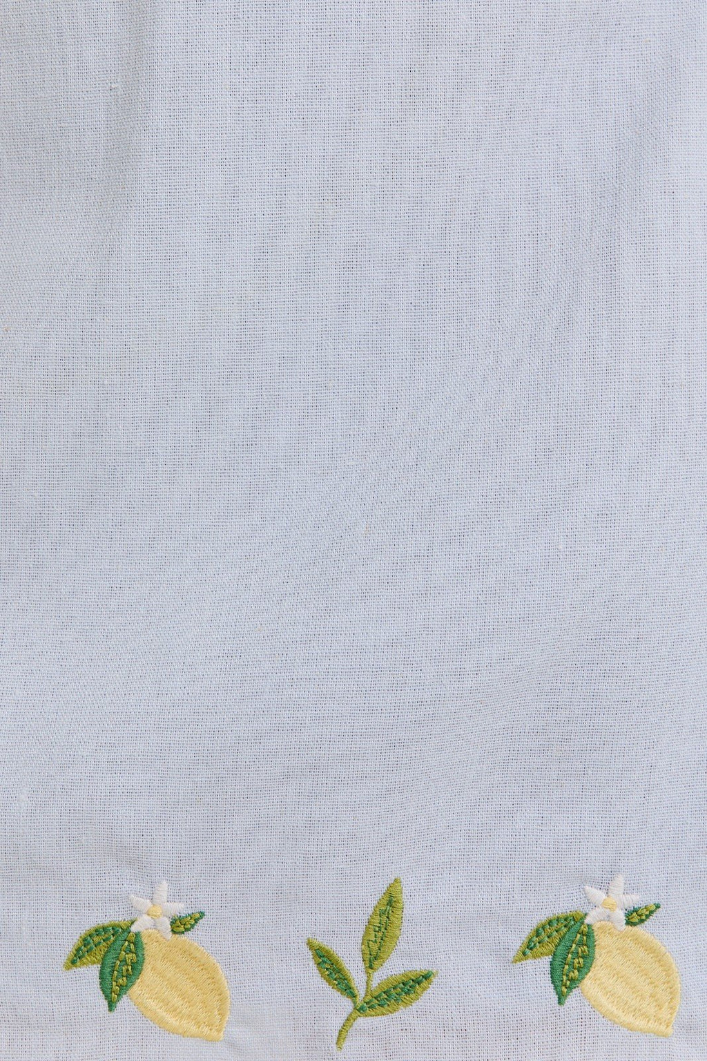 Light blue fabric with vibrant lemon embroidery, perfect for a coastal boutique clothing style.