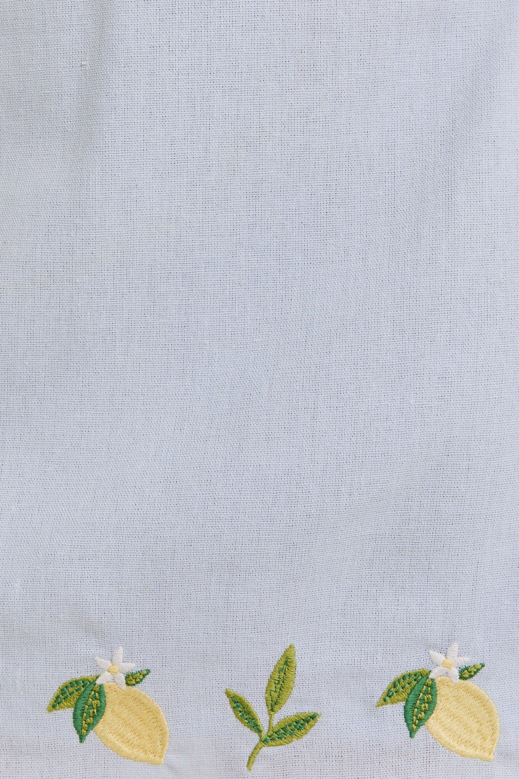 Light blue fabric with vibrant lemon embroidery, perfect for a coastal boutique clothing style.