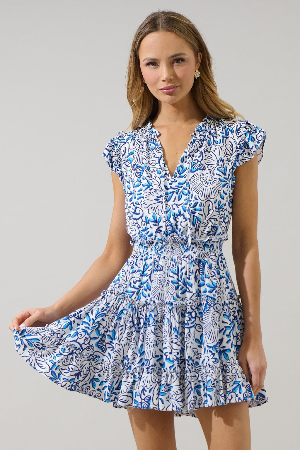 Flora Dress from coastal boutique clothing, perfect for beach days, featuring a blue floral design and ruffled sleeves.