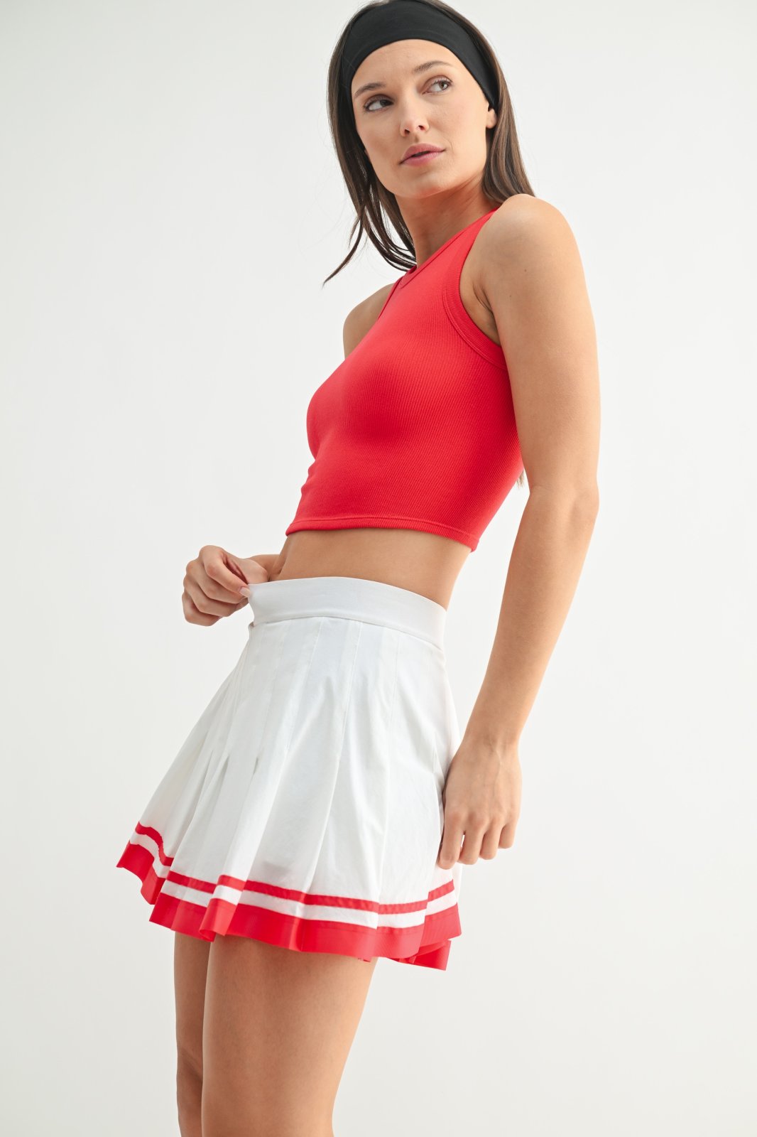 Stylish ruby muscle tank paired with a sporty white pleated skirt, perfect for coastal boutique clothing and beach outings.