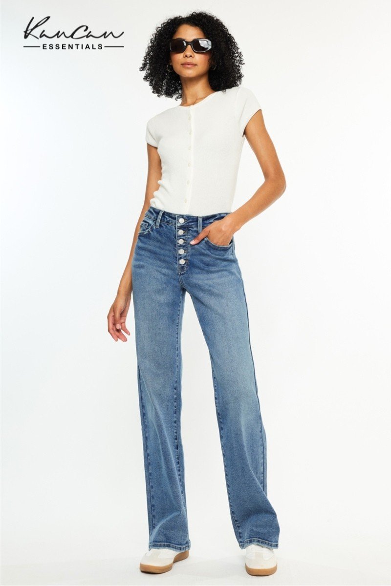 Model wearing KanCan High Rise 90's Flare Jeans with a white shirt, showcasing vintage style at a coastal boutique.