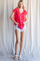 Model wearing a RED AND PINK FLORAL TOP with distressed shorts, showcasing trendy coastal style from Raggdoll Boutique.