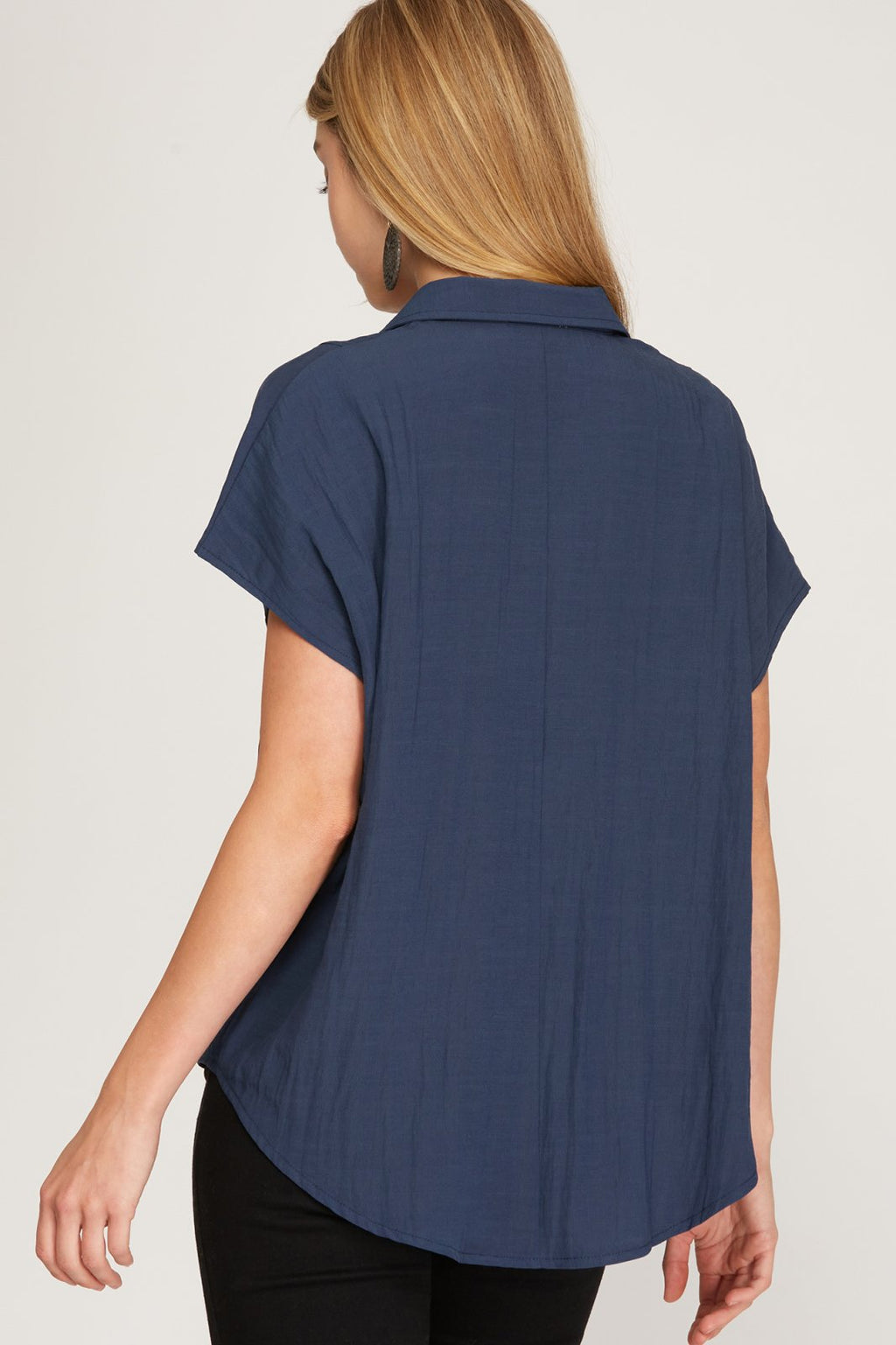 A woman wearing a NAVY BLUE BUTTON DOWN SHIRT with drop shoulders, perfect for trendy coastal style.