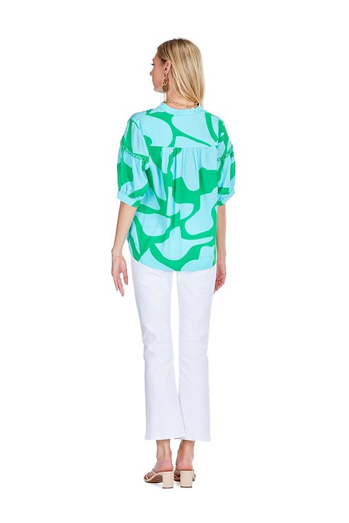 Stylish green and blue patterned top from Port Aransas boutique, paired with white bottoms, ideal for coastal vacations.