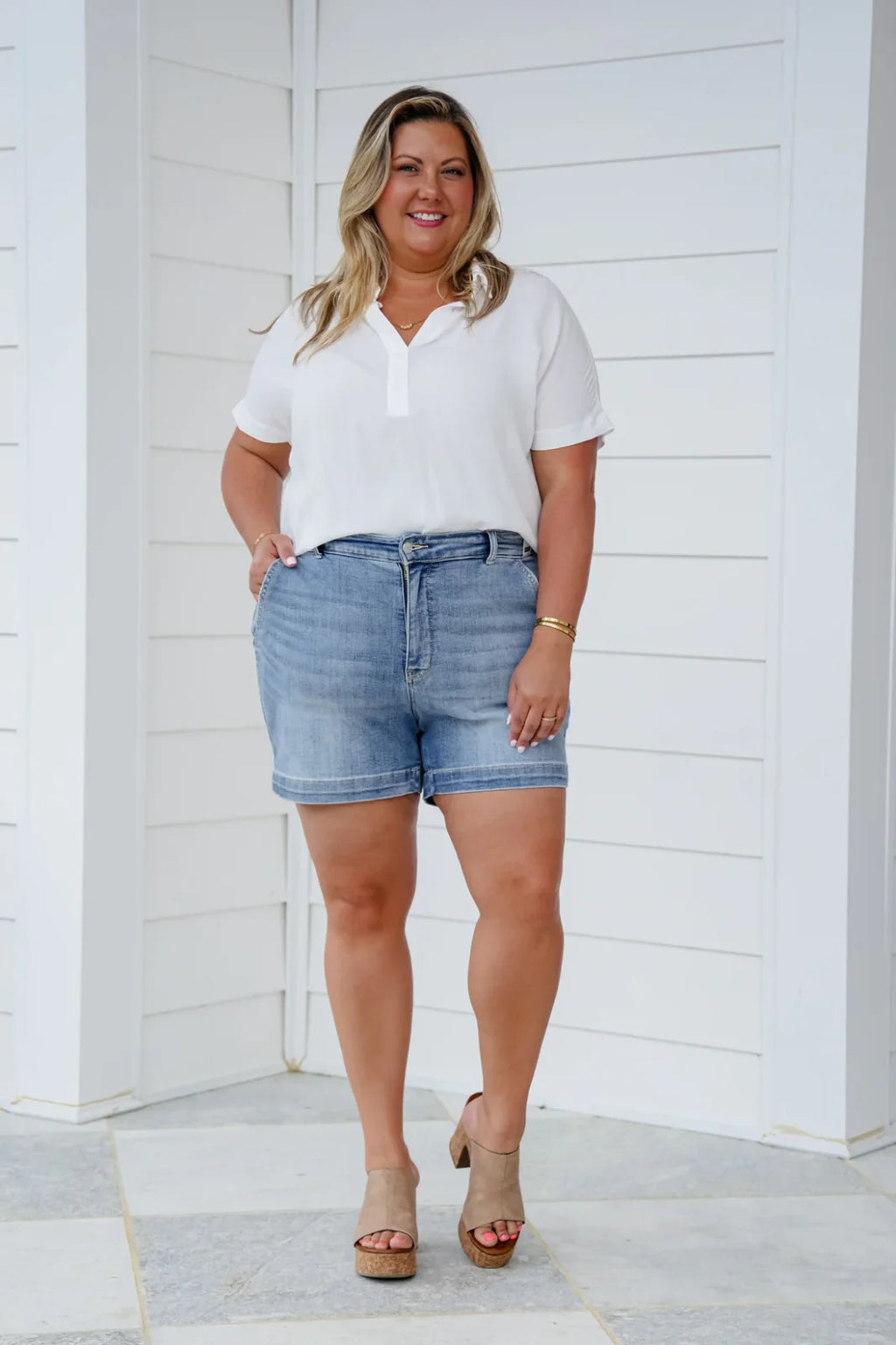 Curvy woman models Judy Blue Plus Trouser Denim Shorts with a stylish white top and heeled sandals, perfect for coastal boutique clothing.