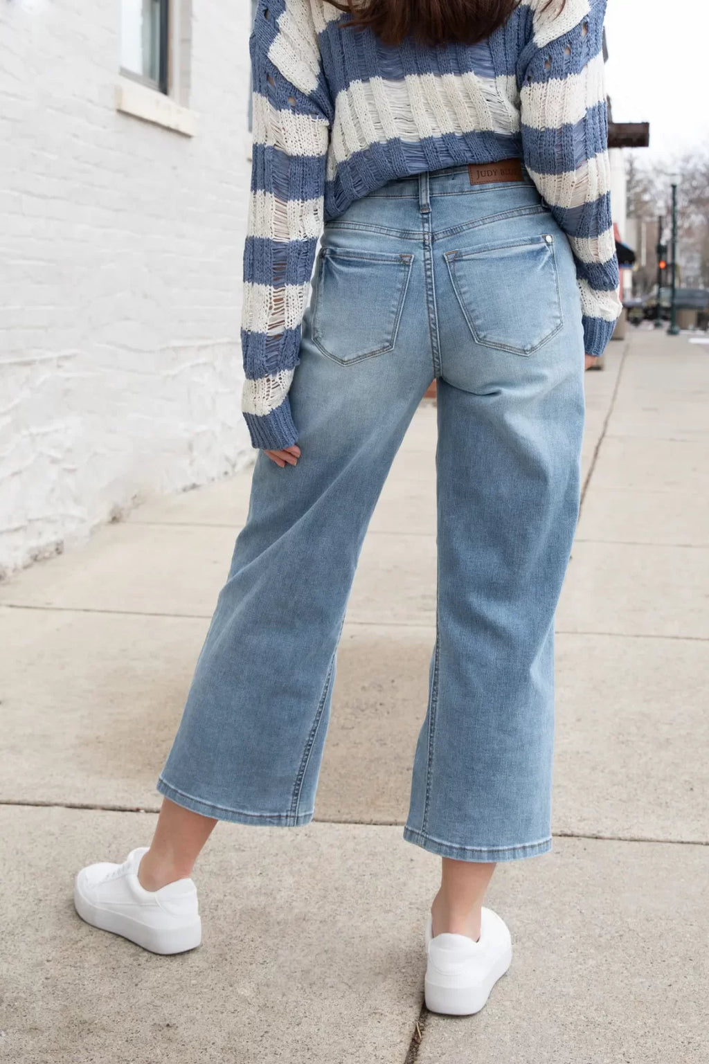 Woman wearing JUDY BLUE HW DOUBLE WB CROP WIDE JEAN with a striped sweater, showcasing trendy coastal style from Raggdoll Boutique.