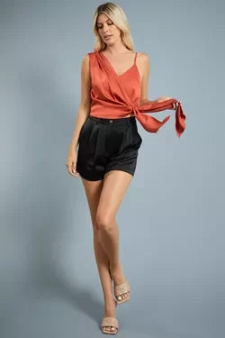 Model wearing BLACK PLEATED SATIN SHORTS with a stylish top, showcasing trendy coastal style from Raggdoll Boutique.