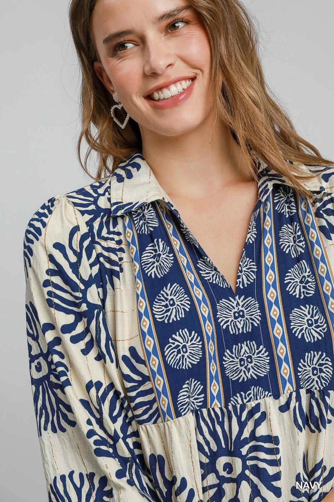 Smiling woman wearing a stylish, floral-patterned shirt from a coastal boutique, perfect for tropical vacations.